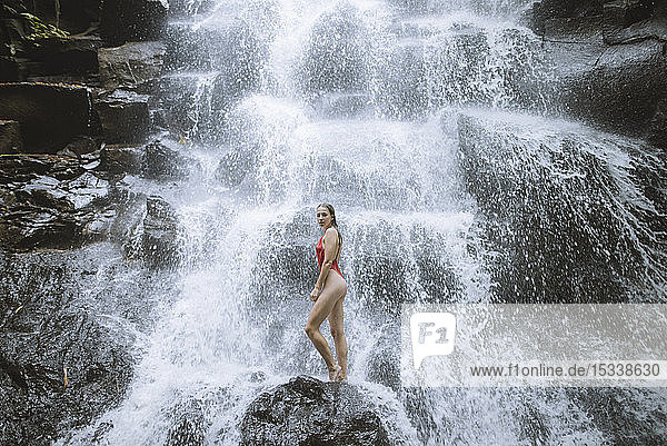 Frau im roten Badeanzug am Wasserfall auf Bali  Indonesien