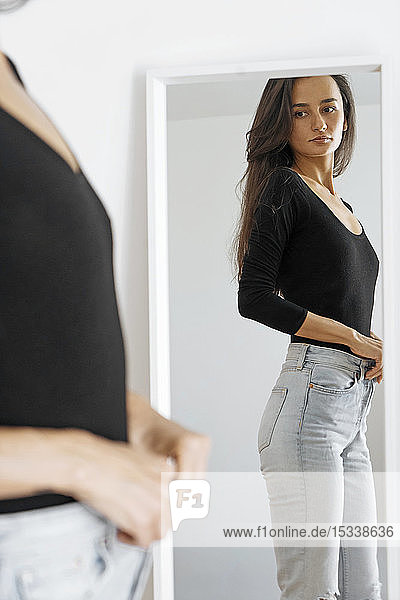 Woman adjusting jeans in mirror