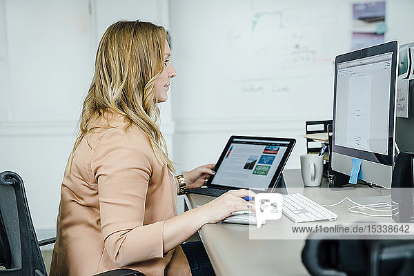 Frau mit digitalem Tablet und Computer im Büro