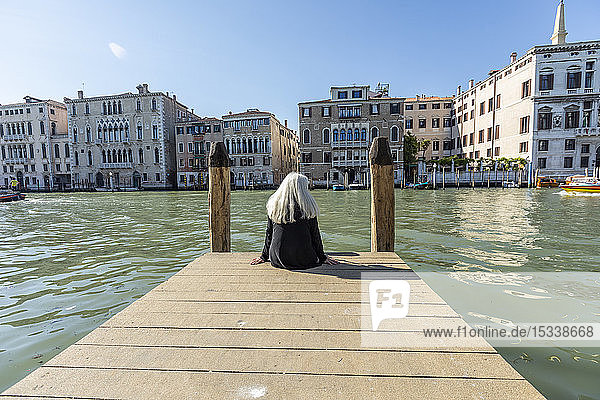 Frau sitzt auf einem Steg am Canal Grande in Venedig  Italien