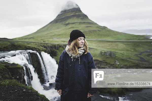 Junge Frau am Kirkjufell und Kirkjufellsfoss in Island