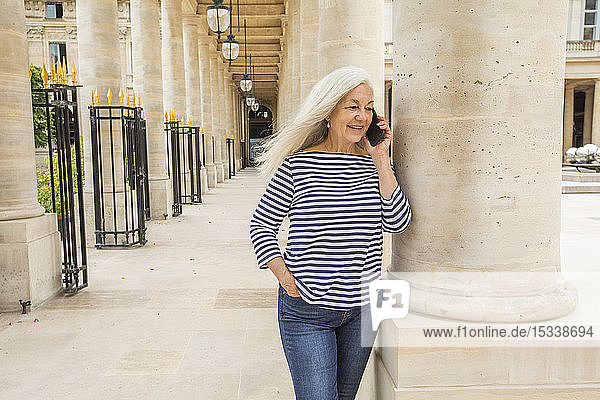 Woman on phone by columns of Palais-Royal in Paris France
