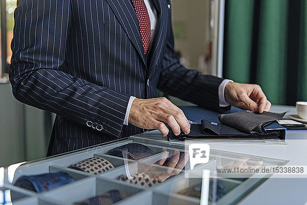 Shop assistant wearing pinstripe suit holding swatches