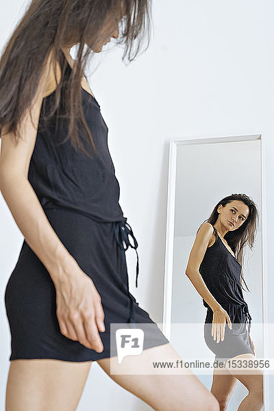 Frau im schwarzen Kleid vor dem Spiegel