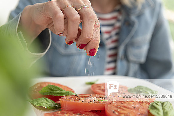 Frau streut Salz auf Tomaten