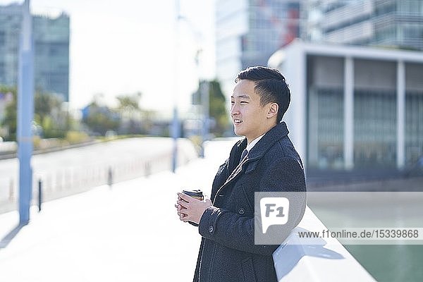 Junger japanischer Geschäftsmann im Freien