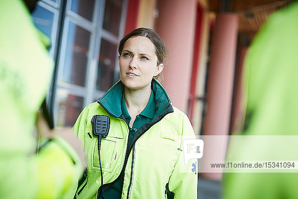 Weibliche Rettungsassistentin für mittlere Erwachsene schaut weg  während sie vor dem Krankenhaus steht