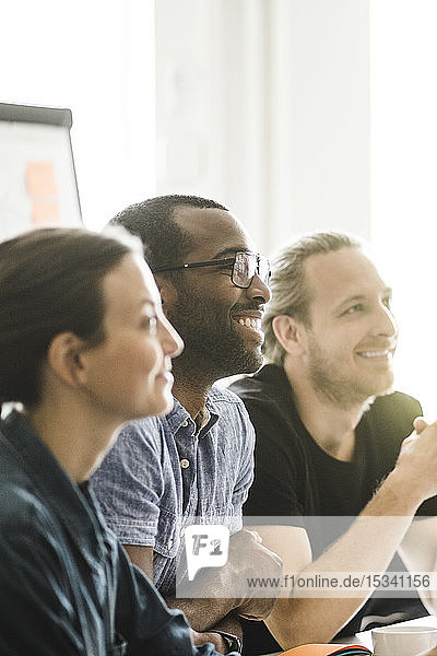 Lächelnde männliche und weibliche Geschäftsleute  die bei Besprechungen im Kreativbüro zuhören