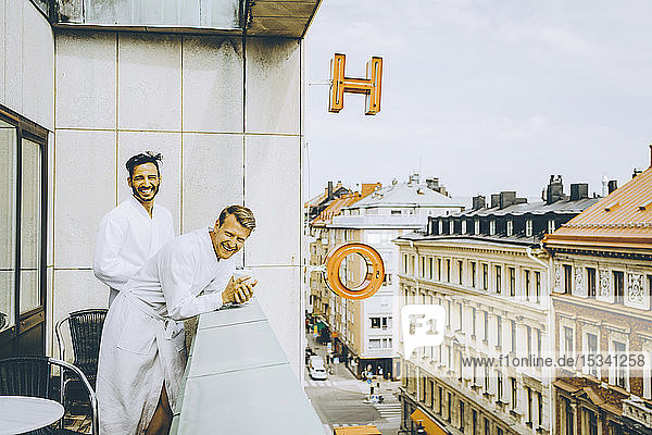 Lächelndes schwules Paar genießt Hotelbalkon