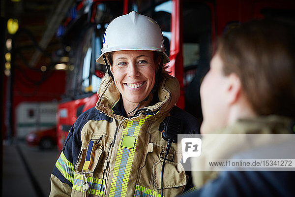 Lächelnde Feuerwehrfrau sieht Mitarbeiterin in Feuerwache an