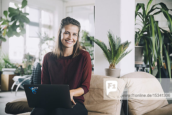 Porträt einer lächelnden kreativen Geschäftsfrau mit Laptop im Büro