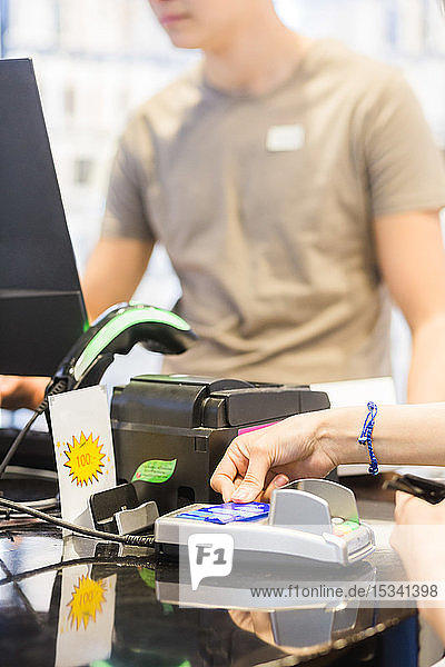 Hände einer Kundin  die an der Kasse mit Kreditkarte bezahlt