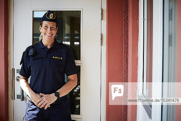 Porträt einer lächelnden Polizistin  die vor der Polizeistation steht