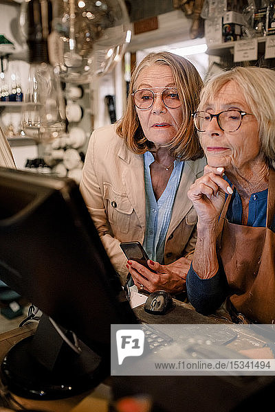 Ältere Kundin und Verkäuferin betrachtet Computermonitor im Baumarkt
