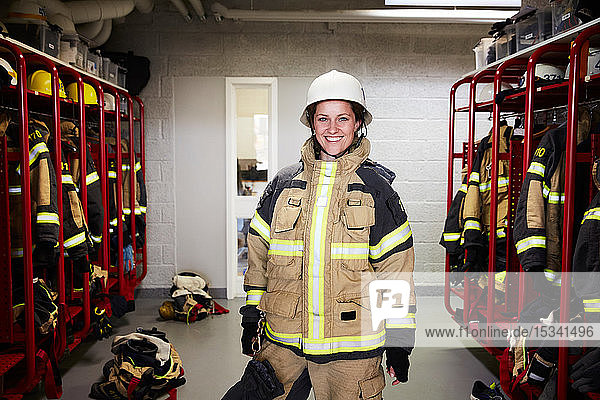 Porträt einer lächelnden Feuerwehrfrau  die in der Umkleidekabine der Feuerwache steht