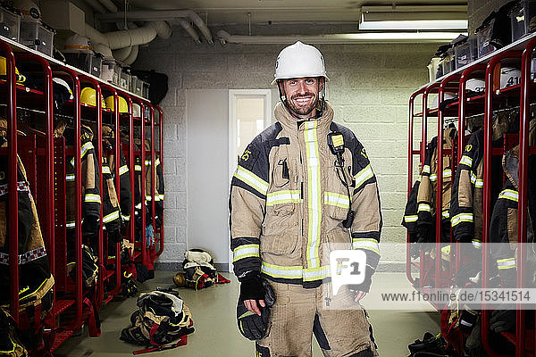 Portrait of smiling male firefighter standing in locker room at fire station