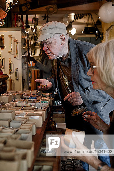 Älterer männlicher Kunde sucht im Eisenwarenladen nach Nägeln von weiblicher Besitzerin