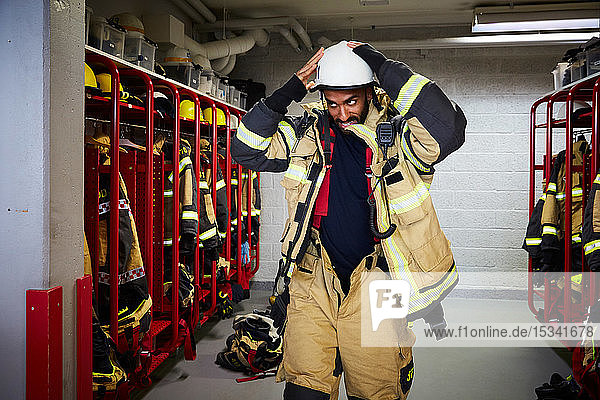 Mittlerer erwachsener Feuerwehrmann mit Arbeitshelm in der Umkleidekabine der Feuerwache