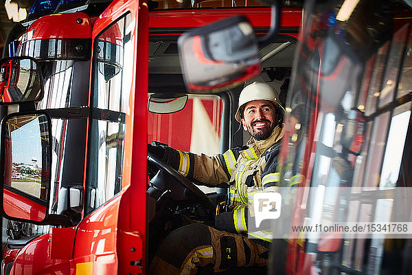Firefighter looking away while sitting in fire truck at fire station