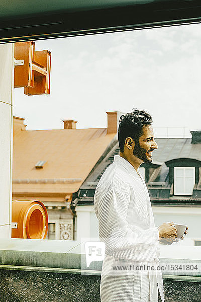 Seitenansicht eines Mannes mit Kaffeetasse auf dem Hotelbalkon