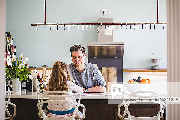 Glücklicher Vater hilft Tochter beim häuslichen Küchenstudium