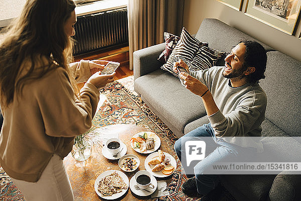 Ehepaar fotografiert Frühstück mit Smartphones im Hotelzimmer