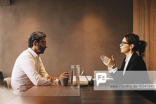 Side view of female lawyer explaining mature client in meeting at office