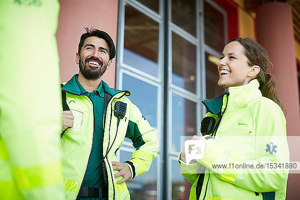 Smiling paramedics talking while standing outside hospital