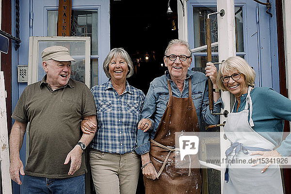 Portrait lächelnder älterer männlicher und weiblicher Mitarbeiter  die am Eingang des Geschäfts stehen