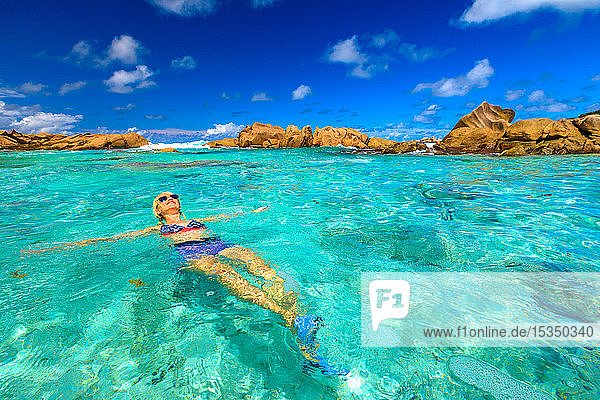 Schwimmbad an der Anse Cocos mit Frau im Bikini  die im türkisfarbenen Wasser des natürlichen Pools am Anse Cocos Beach liegt  der durch Felsformationen geschützt ist  La Digue  Seychellen  Indischer Ozean  Afrika