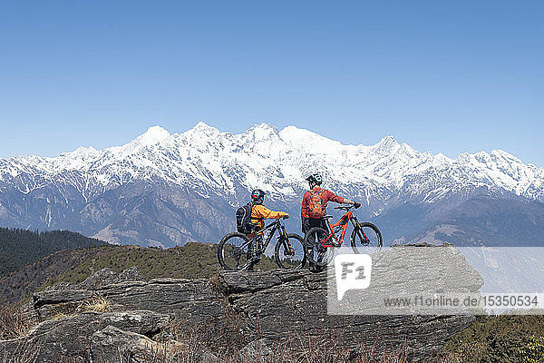 Mountain biking in the Himalayas with views of the Langtang mountain range in the distance  Nepal  Asia