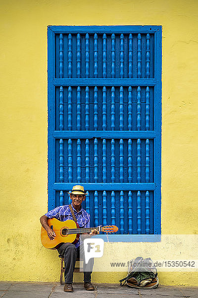 Ein älterer Kubaner sitzt auf einem Stuhl und spielt Gitarre  Trinidad  Provinz Sancti Spiritus  Kuba  Westindien  Karibik  Mittelamerika