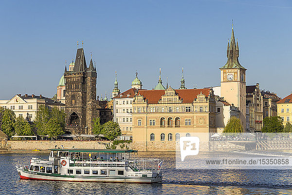 Tourist boat on Vltava River passing the Old Town Bridge Tower and the Old Town Water Tower  Prague  Bohemia  Czech Republic  Europe