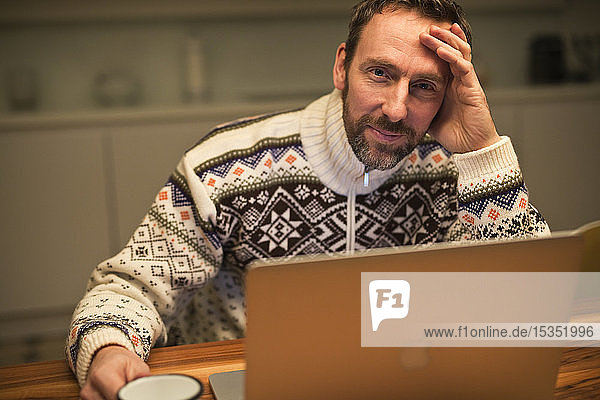 Casual businessman using laptop on table at home