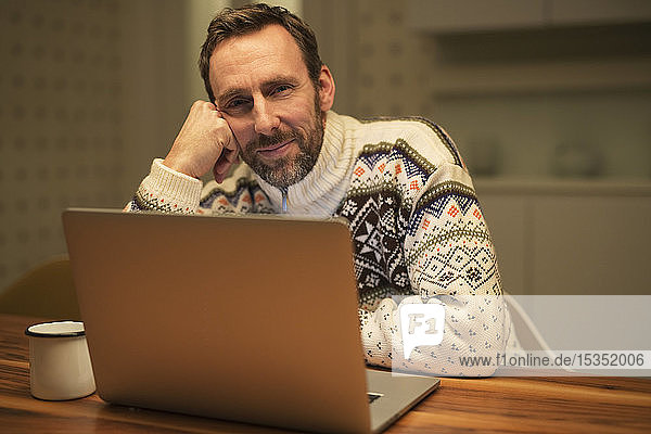 Casual businessman using laptop on table at home