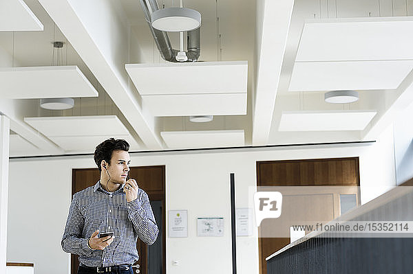 Geschäftsmann benutzt Smartphone im Bürokorridor