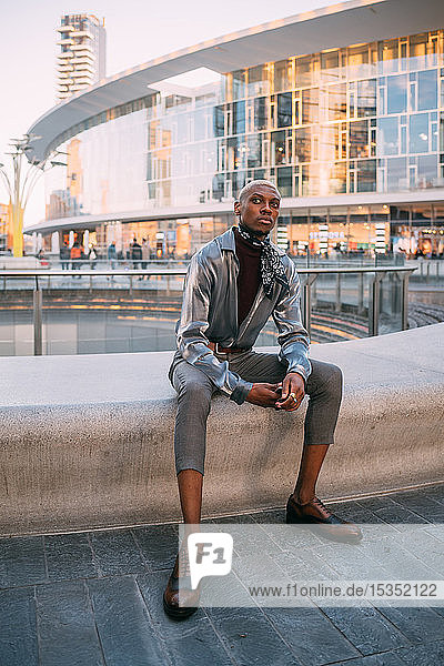 Stylish man sitting by water feature Milan Italy
