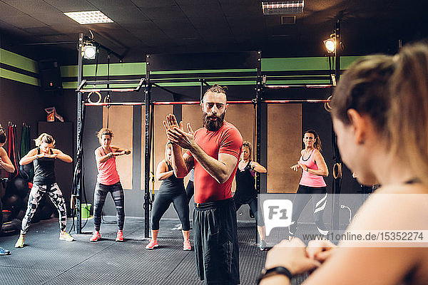 Gruppe von Frauen  die im Fitnessstudio mit einem männlichen Trainer trainieren
