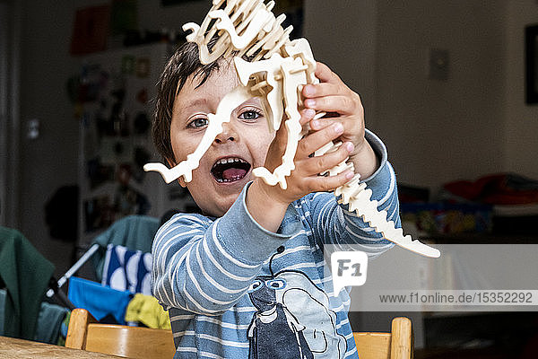 Junge spielt mit Holzdinosaurier