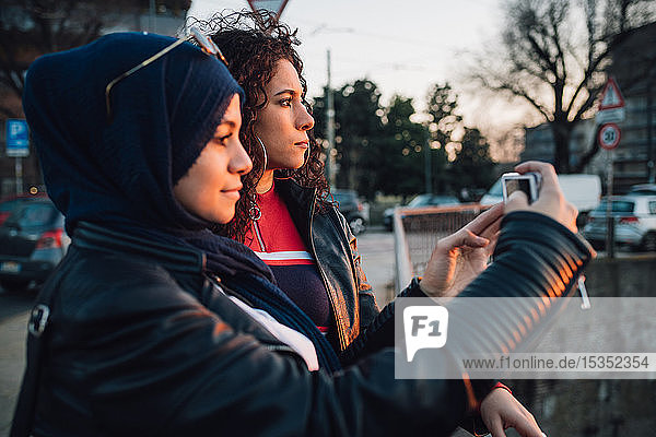 Junge Frau im Hidschab und beste Freundin fotografieren von der Kanalbrücke in der Stadt