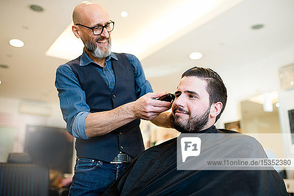 Hairdresser shaving customer's hair in barber shop