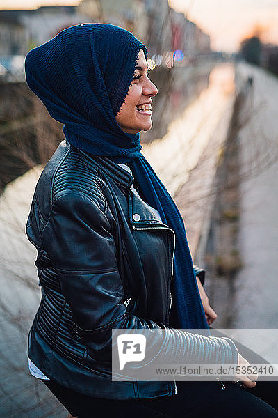 Glückliche junge Frau im Hidschab am Stadtkanal