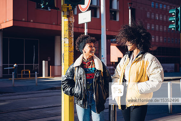 Two cool young female friends chatting in urban street