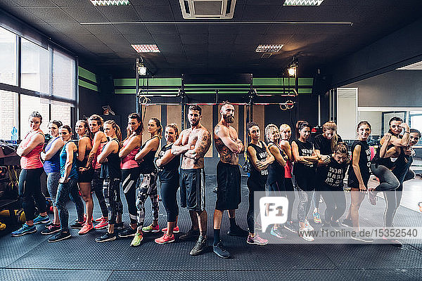 Group of women training in gym  with bare chested male trainers  portrait