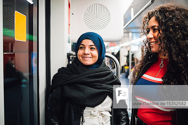 Junge Frau im Hidschab und Freundin in der U-Bahn