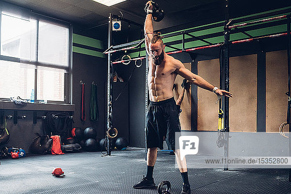 Young man training in gym  lifting kettle bell
