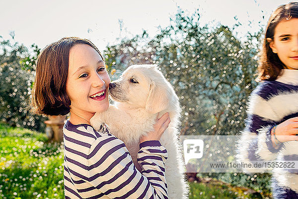 Girl and her friend holding a cute golden retriever puppy in orchard  Scandicci  Tuscany  Italy