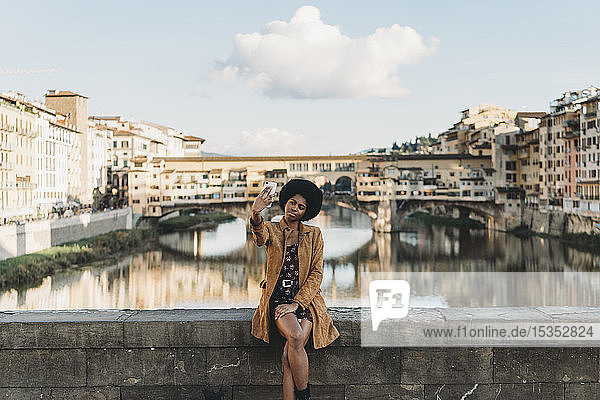 Junge Frau mit Afro-Haaren nimmt sich auf der Brücke selbst in die Hand  Florenz  Toskana  Italien