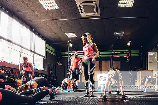 Gruppe von Frauen  die mit einem männlichen Trainer im Fitnessstudio trainieren und Kniebeugen machen