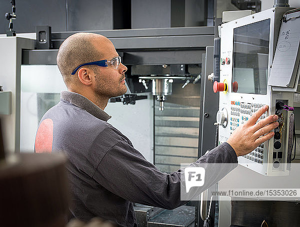 Messerfabrikarbeiter bedient Maschinensteuertafel in der Werkstatt